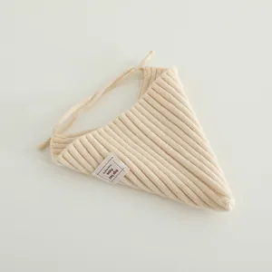 Detail of cream ribbed knit baby bib with soft cotton texture and adjustable straps