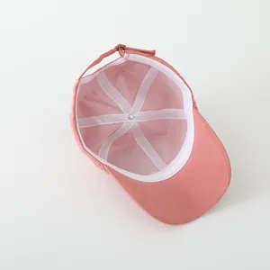 Detail van de roze katoenen pet met witte zweetband en verstelbare metalen gespsluiting
