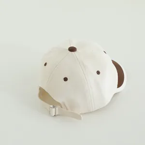Details der verstellbaren Metallschnalle und Nähte an der Baby-Basecap in Cremeweiß und Braun