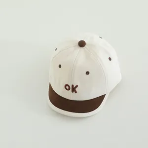 Detaillierte Stickerei des ok-Buchstabens und braune Punkte auf der Baby-Baseballmütze