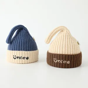 Detailed view of kids knitted beanie hats with unice embroidery and soft wool texture