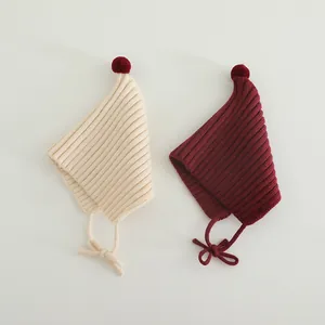 Detail of soft ribbed knit texture on cream and burgundy pointed baby witch hats