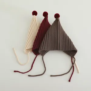 Three colors of knit baby pixie hats with plush pom-poms and ribbed fabric texture