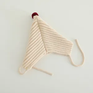 Detail of beige knit baby hat with pointed red pom-pom and secure earflap straps