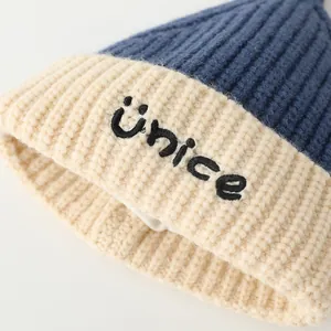 Close-up of color-block knit beanie showing the blue and beige fabric with NICE embroidery