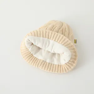 Détail du bonnet en maille crème avec doublure en polaire épaisse et étiquette de marque