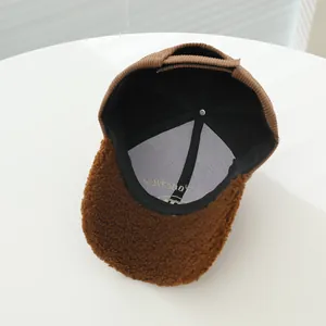 Detail of corduroy baseball cap interior showing white embroidery and warm brown textures