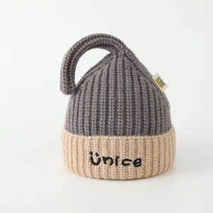 Detailed knit texture of children's two-tone beanie with Ünice embroidery and tail