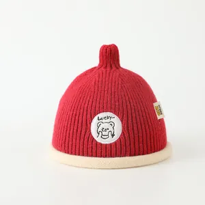 Detail of red knit kids hat with Lucky bear patch and soft ribbed texture
