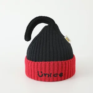 Detail showing the red embroidered NICE logo and smile face on black knit hat