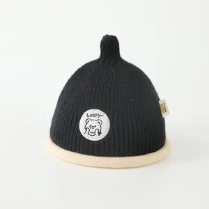 Close-up of black knit beanie for kids with Lucky bear patch and yellow side label