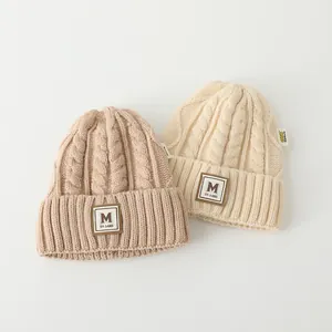 Texture détaillée des bonnets en laine épaisse pour enfants avec écusson M et revers