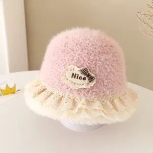 Detailed close-up of pink plush baby bucket hat with lace trim and bow accent