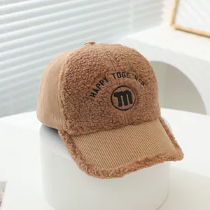 Detail of corduroy and fleece textures on kids winter baseball cap with M embroidery