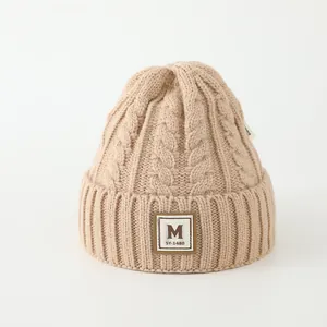 Détails de la maille du bonnet d'hiver kaki avec écusson lettre M et bord à revers épais