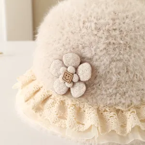 Close-up of plush baby bucket hat with knitted flower, smile button and lace brim
