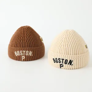 Close-up of BOSTON embroidered letters on thick rib knit beanies in brown and cream