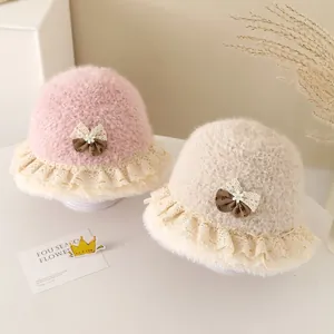 Detail of plush baby bucket hats with lace trim and bowknot decorations in pink and beige