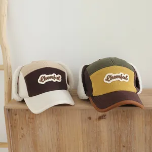 Detalle de gorros infantiles con orejeras de forro polar y bordado decorativo Cheerful