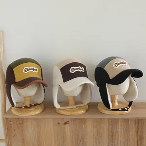 Detalle de gorros de invierno con orejeras y bordado de letras para niños