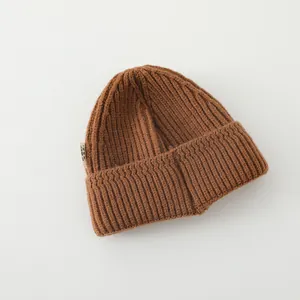 Close-up of caramel ribbed knit beanie showing thick texture and woven side label