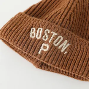 Detailed close-up of brown knit beanie featuring white embroidered BOSTON P lettering