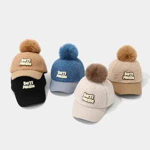 Detail of five winter toddler baseball caps with plush pom-poms and fleece texture
