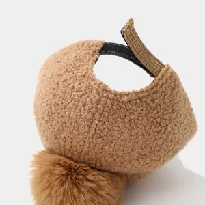 Detailed close-up of brown faux fur kids cap with a plush pompom and adjustable strap