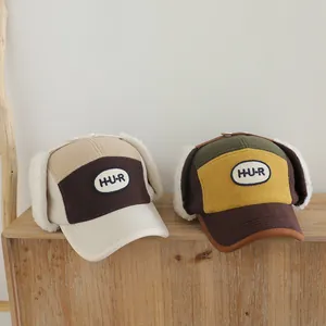 Detalle de gorras de invierno de forro polar bicolor con orejeras y parche de H-U-R