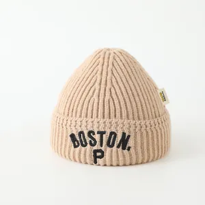 Detail of beige knit beanie with Boston P embroidery and soft ribbed texture for kids