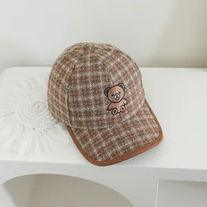 Détail d'une casquette de baseball à carreaux marron pour enfant avec broderie ours