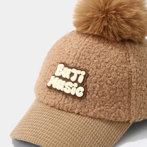 Close-up of brown plush winter baseball cap with faux fur pom pom and MUSIC patch detail