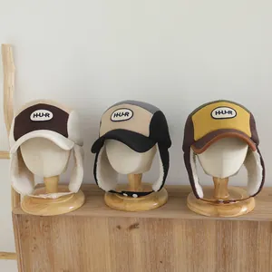 Vista detallada de tres gorros de aviador para niños con forro polar y parches H-U-R