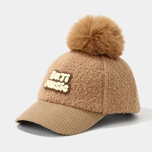 Detail view of winter brown plush baseball cap with fuzzy pompom and corduroy brim