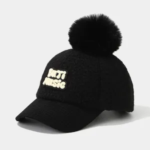 Detail of black winter cap featuring fluffy fur pom-pom and 3D BITI MUSIC embroidery