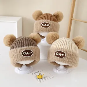Winter warm knit baby hat with dual pom-poms and ear flaps in brown and beige tones
