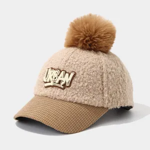 Detail of warm lamb wool cap featuring a brown pompom and 3D Urban letter patch
