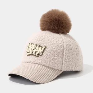 Detail of winter sherpa baseball cap featuring urban patches and brown faux fur pompom