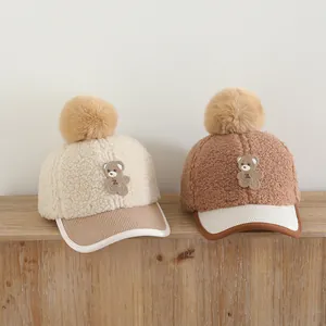 Detail of children's fleece baseball caps featuring pom-pom and knitted teddy bear patch