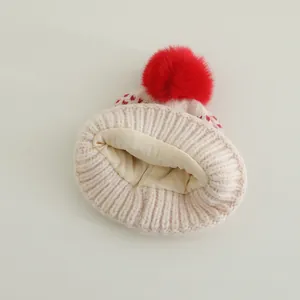 Thick knit baby winter hat with red pom-pom and heart pattern on warm fleece lining