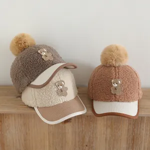 Close-up of fluffy kids' winter baseball hats with plush fur balls and bear embroidery