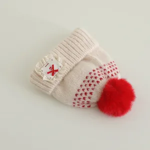 Detail of baby knit hat showing red heart patterns and lace bow handmade patch