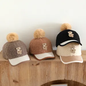 Detailed view of fleece baseball caps with faux fur pom-poms and cute teddy bear patches