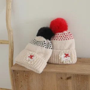Detailed view of knitted kids hat featuring lace bow and handmade tag on wood background