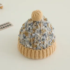 Detail der mehrfarbigen Strickmütze für Kinder mit beige geripptem Saum und weichem Pompon