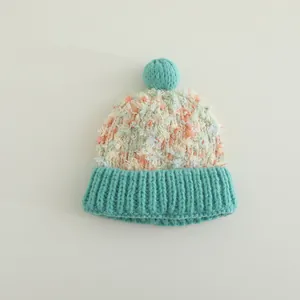 Detailansicht der Strickmütze mit bunter Schneeflocken-Textur und flauschigem Pompon