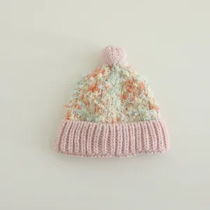 Detailaufnahme der flauschigen bunten Wintermütze mit weichem Bommel und Rippstrickrand