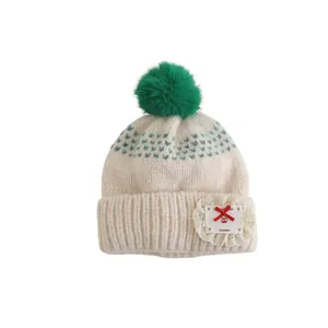 Off-white knit winter hat for kids with green pompom and handmade lace bow patch