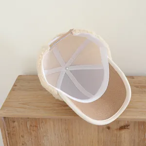 Détail d'une casquette en polaire crème avec visière en velours côtelé marron et bande interne