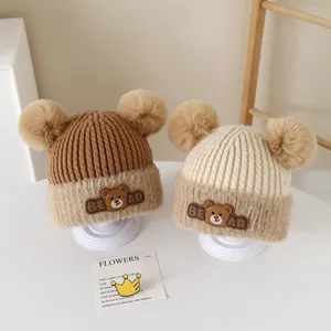 Cute baby winter knit hat with double fur pom-poms and cartoon bear patch detail